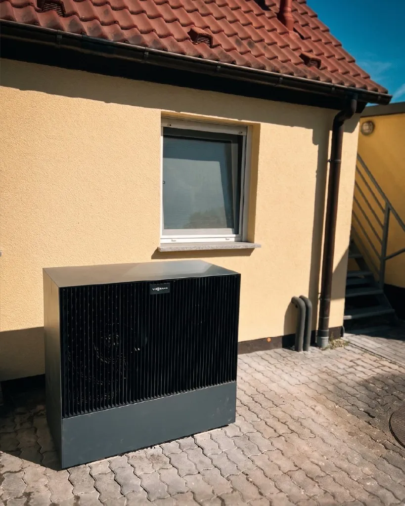 Dunkle Viessmann-Wärmepumpe vor einer gelb verputzten Hauswand